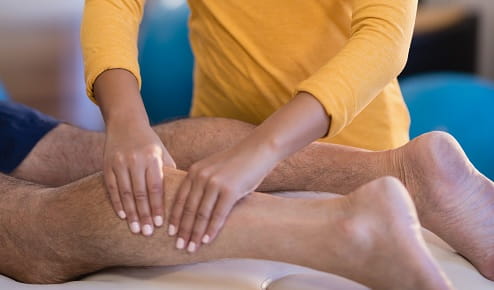 A Woman Giving a Man a Leg Massage at Home