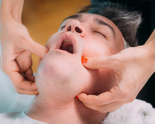 Client treating TMJ with a TMJ massage